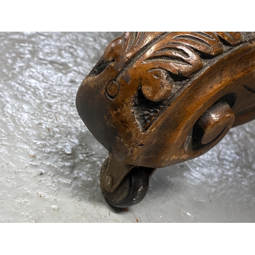 12 - Antique mahogany table with oval top, on central pedestal with ornately carved legs and castors