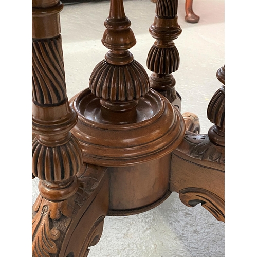 12 - Antique mahogany table with oval top, on central pedestal with ornately carved legs and castors