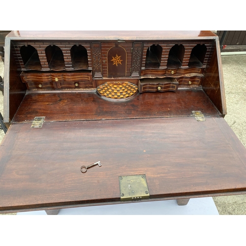 42 - Antique mahogany four drawer bureau, the drop-down front reveals smaller drawers and highly decorati... 