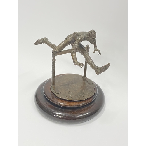 75 - A Bronze hand sculpture of an Olympic hurdler on wooden swivel base, approx. overall height 15cm