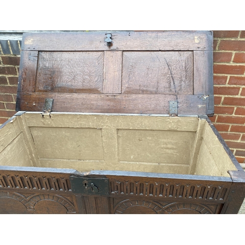 9 - Large antique oak hinged wooden chest with heavy carved detailing to front panel