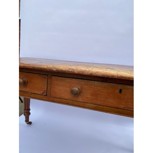 113 - Antique pine side table with two drawers, on castors A/F