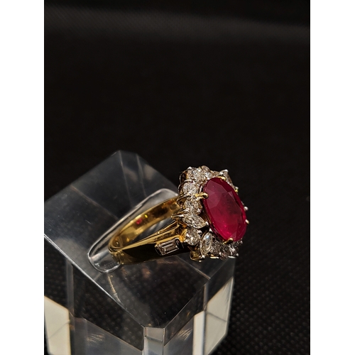 18ct yellow gold Ruby and diamond cluster ring, set with central oval ruby of approximately 4ct, surrounded by clusters of brilliant cut diamonds, to either side of the shoulder are two marquise shaped diamonds with small baguette diamonds  totalling approx. 1.45ct. approx. size N/O, approx. gross weight 9.3g approx. overall length 2cm x 2cm width. Please also see Lot 217 for matching earrings