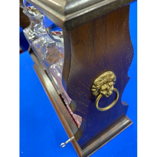 66 - Vintage mahogany and brass tantalus with three cut glass decanters, with key