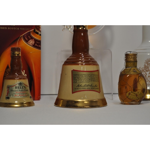 63 - A collection of different bottles of whisky's including Stylish Whisky globe bottle, bells and a bot... 