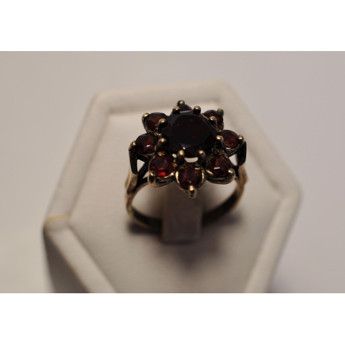 48 - 9ct yellow gold rings (x2), one featuring a red stone cluster approx. size O, one with oval cabochon... 