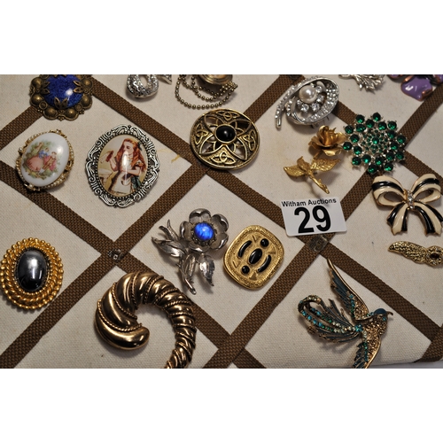 29 - A board containing a selection of various brooches/ pin badges in various shapes and designs