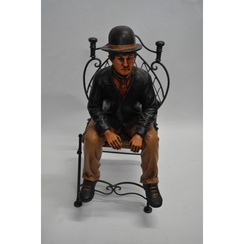 128 - Large Charlie Chaplin figure seated on a heavy metal folding seat