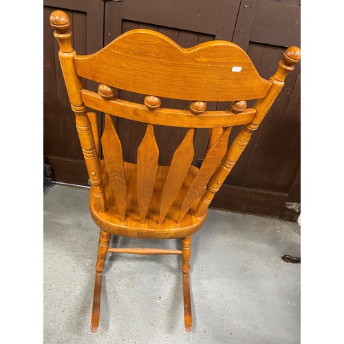 147A - A large solid wood rocking chair with tall slat back backrest design and turned supports.