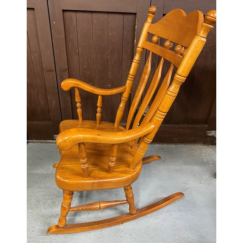 147A - A large solid wood rocking chair with tall slat back backrest design and turned supports.