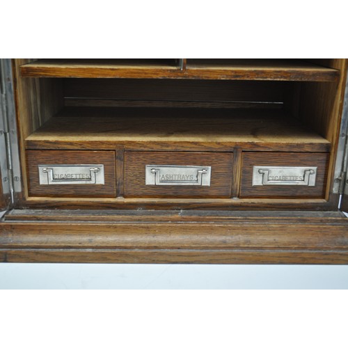 6 - A Wooden smokers cabinet with oak panel doors. The three drawers to the interior labelled cigarettes... 