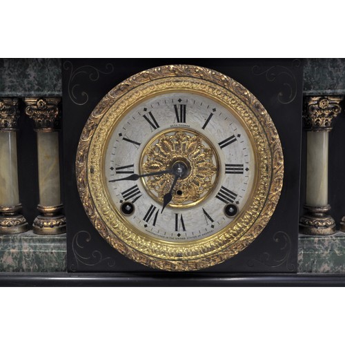 50 - An Antique Faux Slate, Ormolu, and Marble effect American Mantle Clock with twin columns and lion he... 