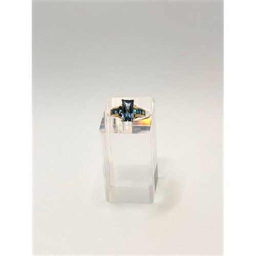 250 - 9ct yellow gold ring with faceted rectangular blue stone - possibly topaz, with co-ordinating square... 