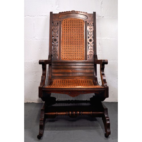 104 - Antique American style coil sprung cane rocking/rocker chair with carved detailing