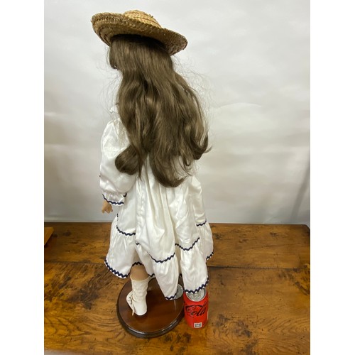 203 - Doll with porcelain head and limbs, with straw boater hat and removable stand, approx H74cm