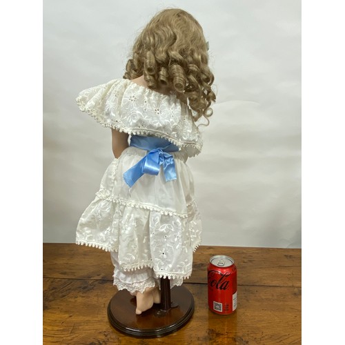 204 - Hand made doll on stand, porcelain face and limbs, cheeky expression to face with removable hairpiec... 