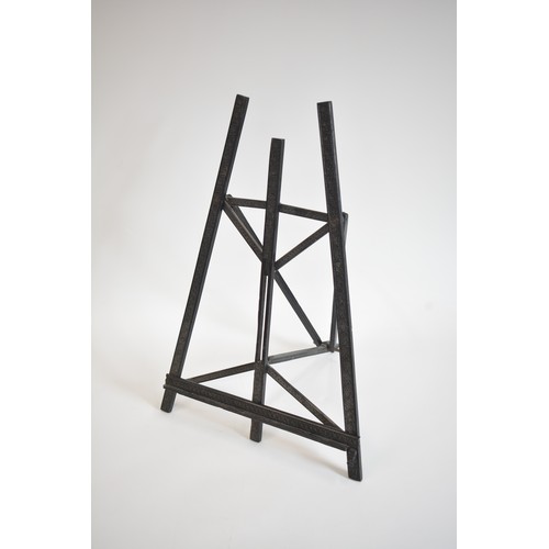 63 - Vintage ebonised Easel with carved scroll foliate design. size 40cms widest point, 62 cms tall