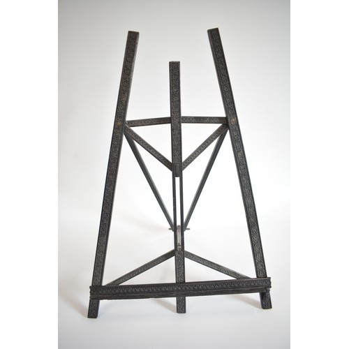 63 - Vintage ebonised Easel with carved scroll foliate design. size 40cms widest point, 62 cms tall