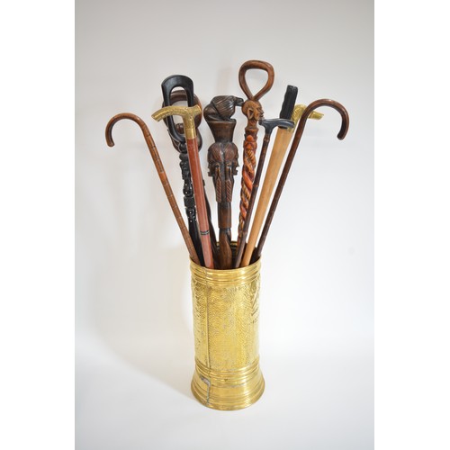 93 - Brass stick stand containing a quantity of African, some tribal hardwood, and other walking canes an... 