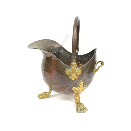 93 - Antique hammered copper and brass helmet coal scuttle being raised on three claw feet