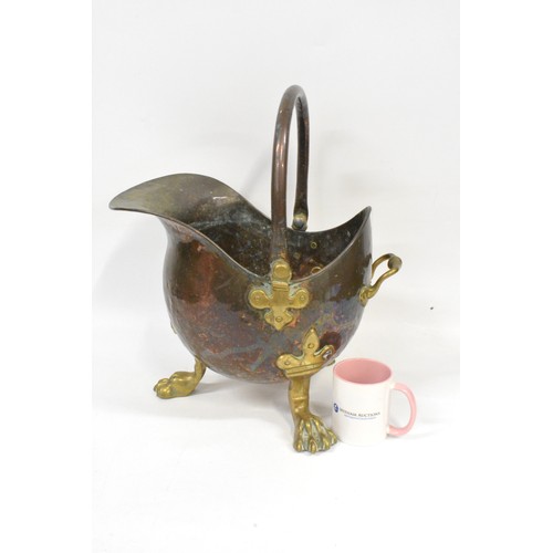 93 - Antique hammered copper and brass helmet coal scuttle being raised on three claw feet