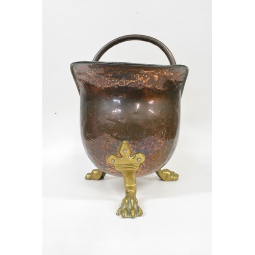 93 - Antique hammered copper and brass helmet coal scuttle being raised on three claw feet