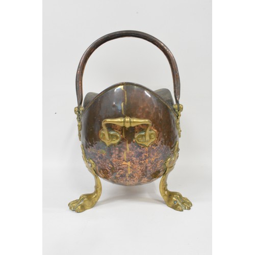 93 - Antique hammered copper and brass helmet coal scuttle being raised on three claw feet