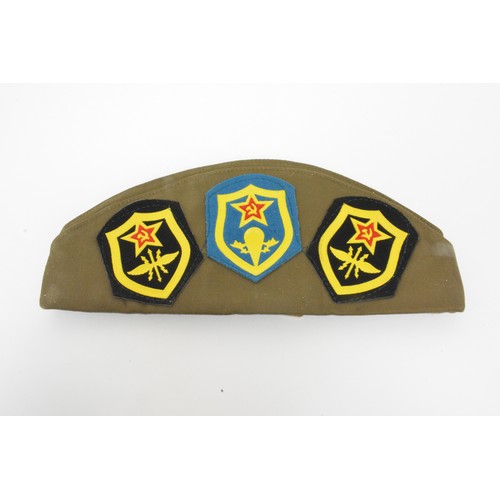 140 - Russian Military Cap with assortment of various metal badges.