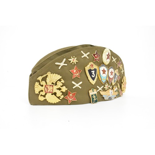 140 - Russian Military Cap with assortment of various metal badges.