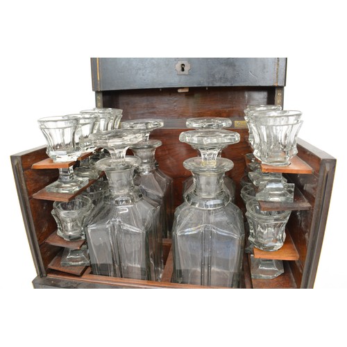 7 - Antique Liqueur Tantalus, ebonised wooden case which opens up to reveal sixteen glasses and  four ca... 