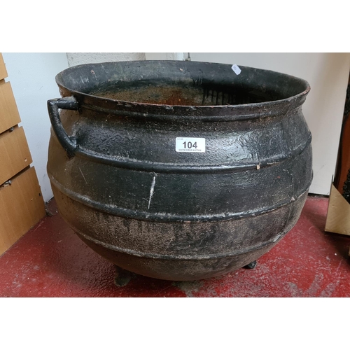 104 - Very large black cast metal cauldren two handles. Missing one of its 3 feet