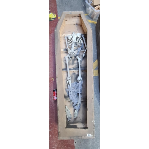 82 - Wooden coffin with a partial faux skeleton, 184cm x 63cm x 30cm tall.