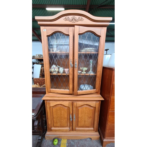 599 - Vintage light wood two-tiered display cabinet with glass fronted doors and and lower cabinet with a ... 