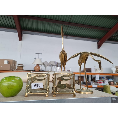 690 - Four brass items including two candle holders with glass inserts and two heron/cranes