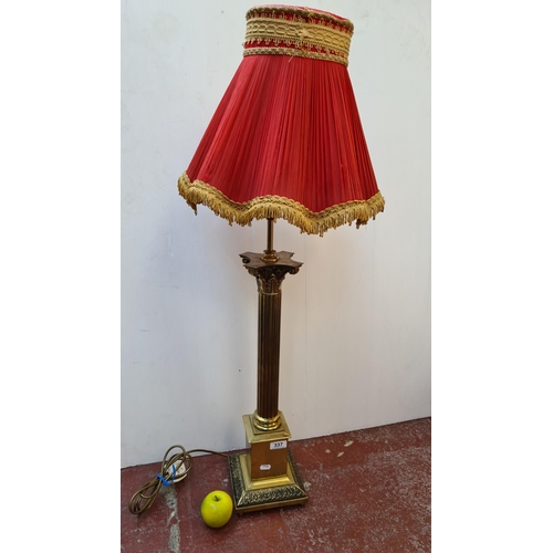 337 - Tall brass Corinthian column lamp with beautiful red and gold trimmed lamp.