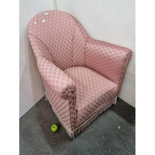 567 - Pink open armchair with fringed detail on castors, in good condition. Overall height 81 cm.