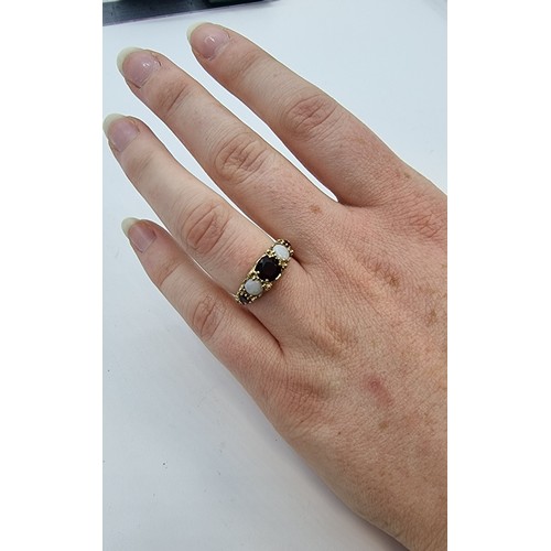 16 - An antique 9 carat gold 5 stone ring, of garnets and opals. With foliate design shank. Size L, weigh... 