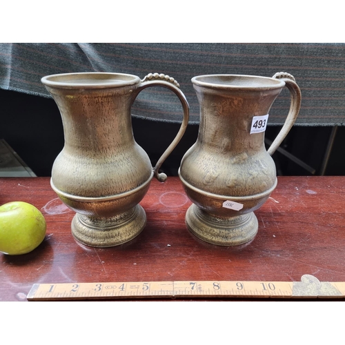 493 - A pair of matching Grecian style cast brass jugs.