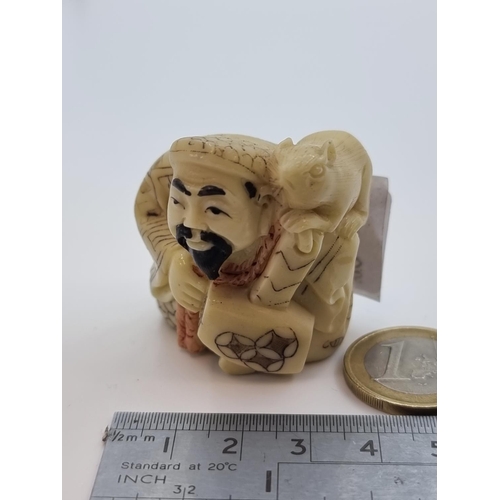 6 - A bone carved netsuke, with maker's mark to base, depicting a Chinese figure with a rat carved to hi... 