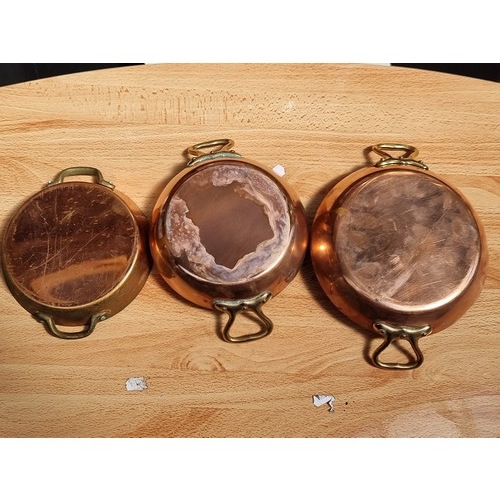 386 - Set of three copper dishes with brass handles in the shape of miniature paella pans.