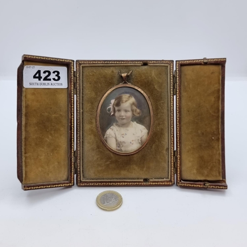 423 - An antique hand painted water colour depicting a young girl in a copper frame enclosed in a leather ... 