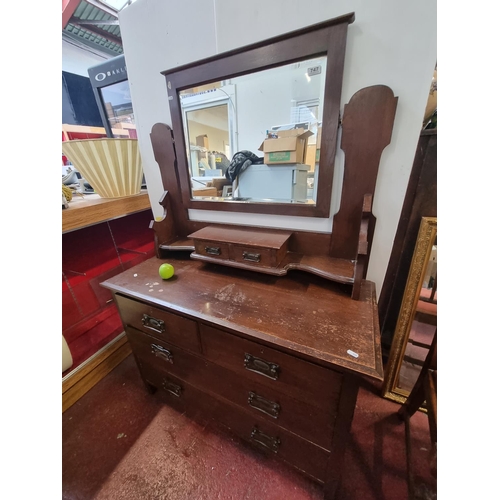 747 - An Art nouveau wooden dresser with seven drawers and a bevelled swivel mirror with brass handles.