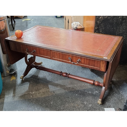 An Antique Drop Leaf Coffee Table with a Red Leather Top and Brass Claw Feet on Castors