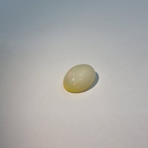 65 - A white oval cabochon Opal with lovely colours including reds. . Weight 3.7 carats, with IDT certifi... 