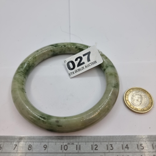 27 - A mottled jade bangle, stone cold to touch. Internal diameter of bangle 6.5cm. A nice piece.