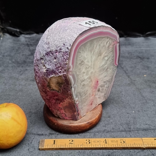 155 - A large piece of pink crystal, sliced to show the cross-section of the layers, and mounted on a wood... 