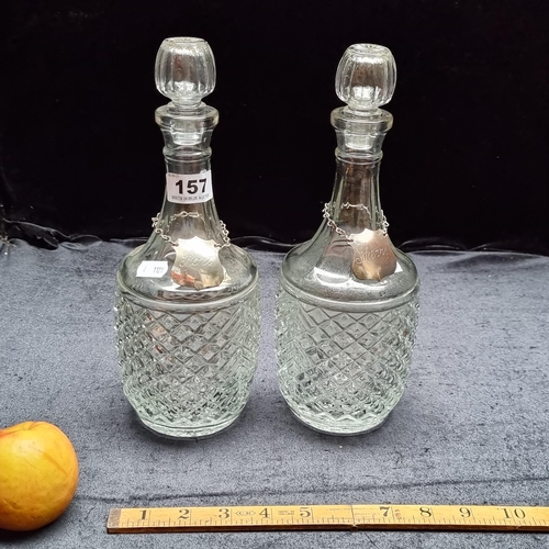 157 - Two cut glass decanters with stoppers. Both have chained metal plaques around the neck, One reading ... 