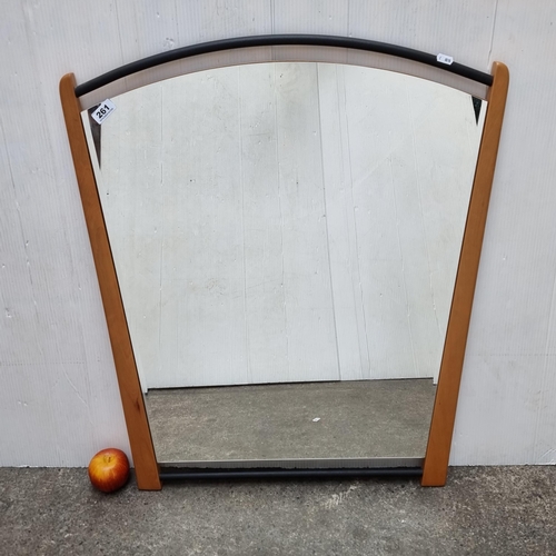 261 - A large wedge-shaped, bevelled wall mirror with light wood and metal detail. Mirror has wire on reve... 