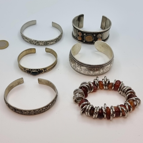 9 - A collection of five bangles, two stone set examples, three floral designed pieces. Together with a ... 