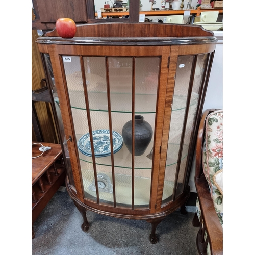 555 - A demi-lune display cabinet with three glass shelves, original key and claw ball feet. Lined with fa... 